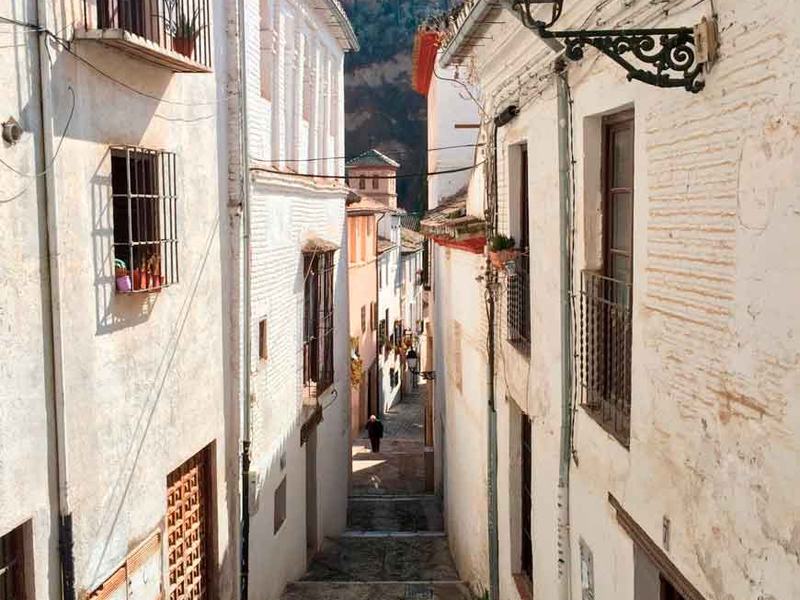 Whitewashed lane in the Albaicín with the Alhambra behind